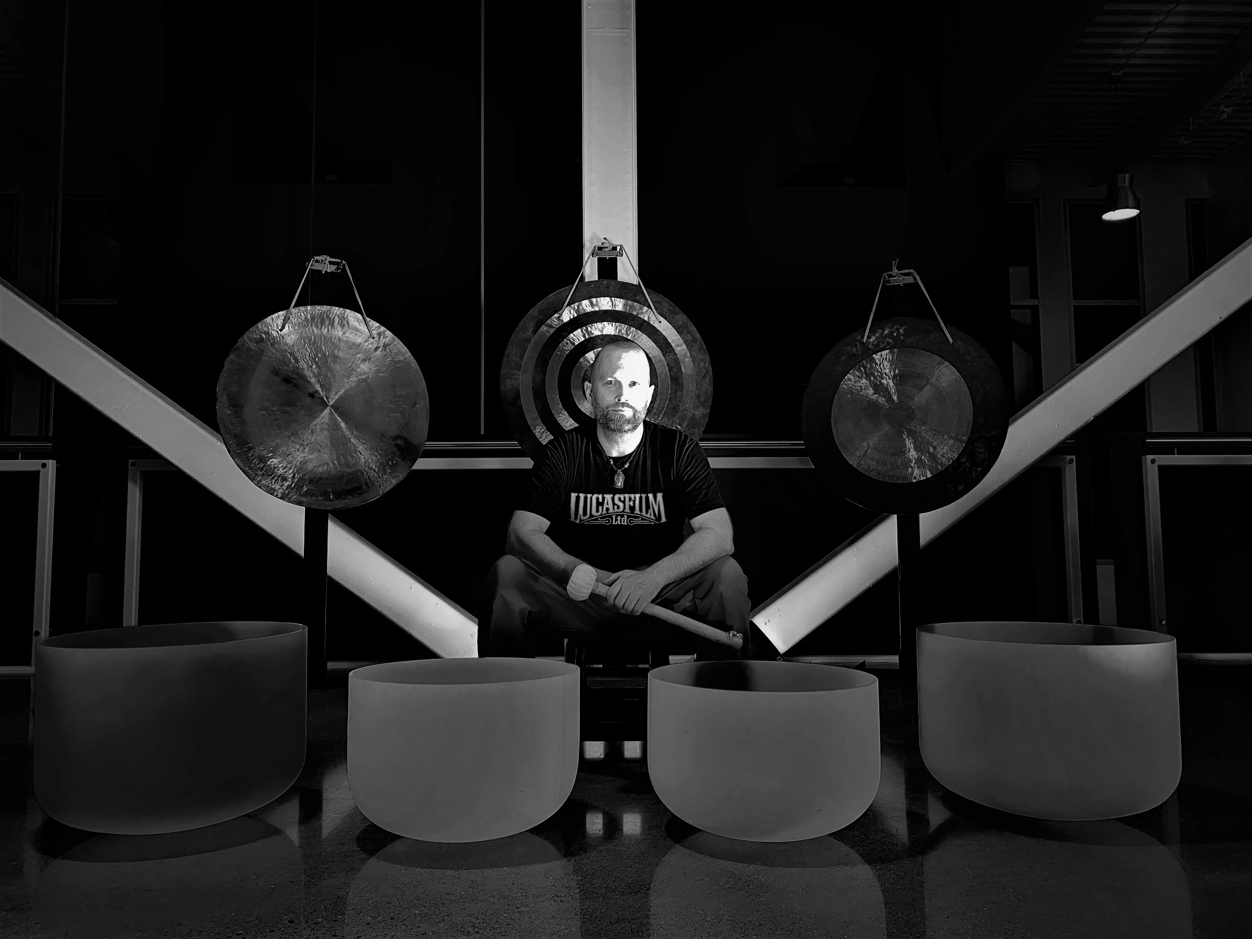 Wayne Noel seated among gongs and large crystal singing bowls